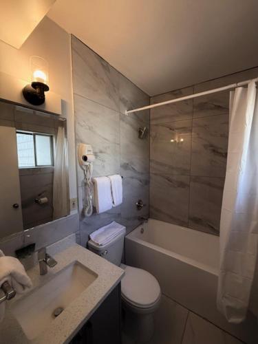 a bathroom with a toilet and a tub and a sink at Schell Motel in Vernon
