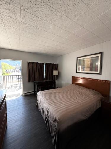 a bedroom with a bed in a room with a window at Schell Motel in Vernon