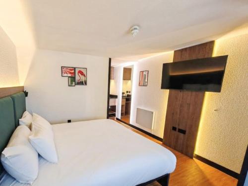 a bedroom with a white bed and a flat screen tv at The Crossway Hotel, Coventry Walsgrave, Part of AG Collection in Coventry