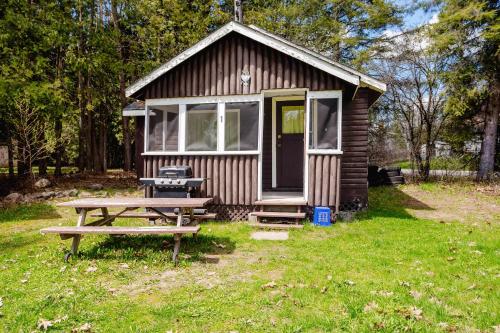 a small shed with a picnic table and a picnic table at 2-Bedroom Cottage #1 - Ambleside in Kawartha Lakes