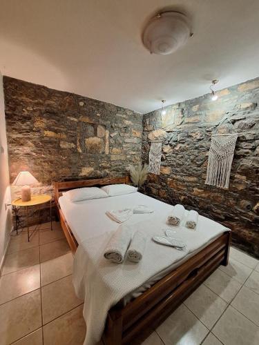 a large bed in a room with a stone wall at Sidirounta Village Apartment in Sidiroúnta