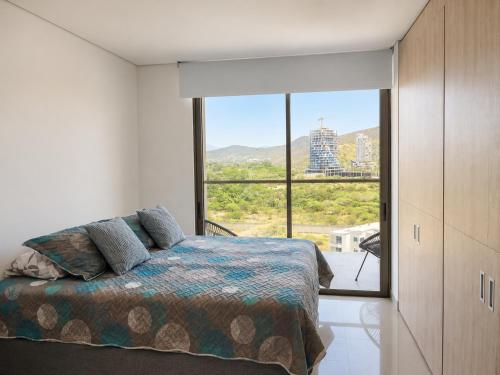 a bedroom with a bed and a large window at Reserva del Mar II, Aparta suite cerca de la playa in Gaira