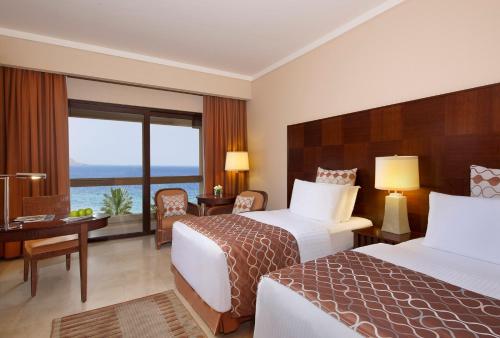 a hotel room with two beds and a view of the ocean at InterContinental Aqaba by IHG in Aqaba