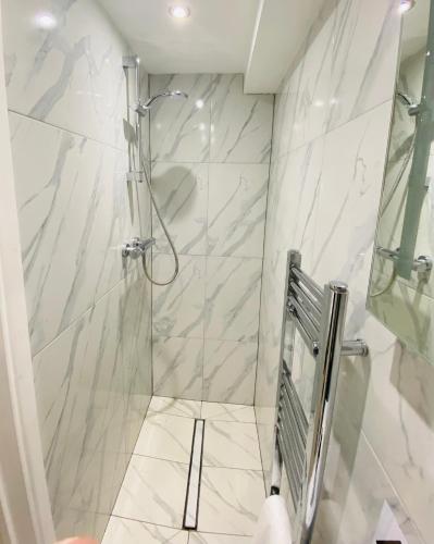 a bathroom with a shower with white marble walls at Old George Hotel in Milton Keynes