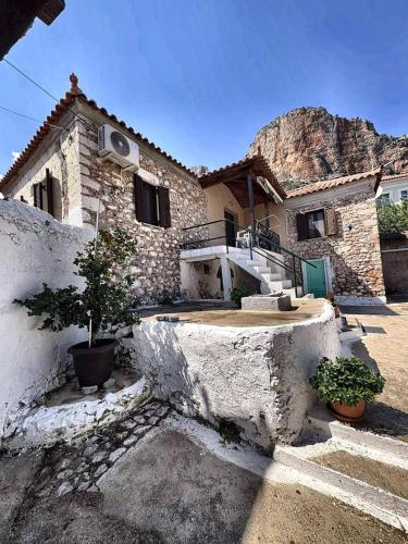 a stone house with a mountain in the background at Leos Traditional Holiday House in Leonidio