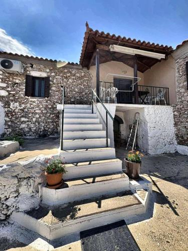 a stone building with stairs in front of a house at Leos Traditional Holiday House in Leonidio