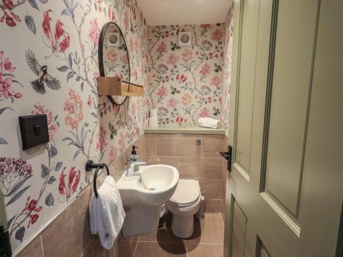 a bathroom with a sink and a toilet with floral wallpaper at Fogga Croft in Skipton