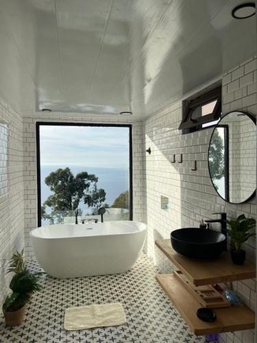 a bathroom with a large tub and a large window at Skidala Cottage in Batumi