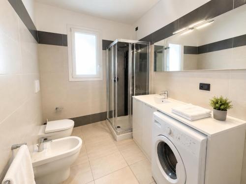 a bathroom with a toilet sink and a washing machine at Villa Marina Apartments - Agenzia Cocal in Caorle
