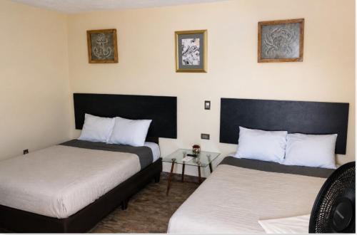 a bedroom with two beds and a glass table at Habitación arena, Paseo Durango in Durango