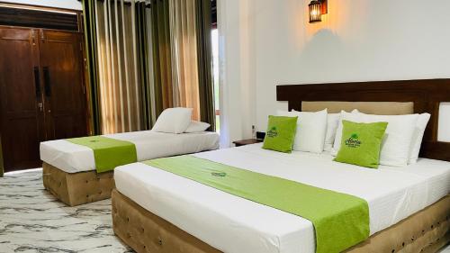 two beds in a hotel room with green and white at Aloria Sigiriya in Sigiriya