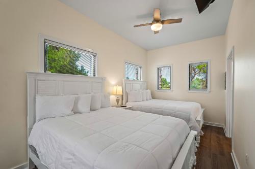 a white bedroom with two beds and a ceiling fan at St James Bay Golf & Pickleball Resort in Big Blackjack Landing