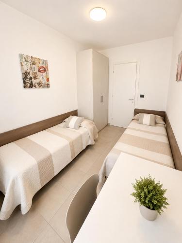 two beds in a room with white walls and tables at Villa Marina Apartments - Agenzia Cocal in Caorle