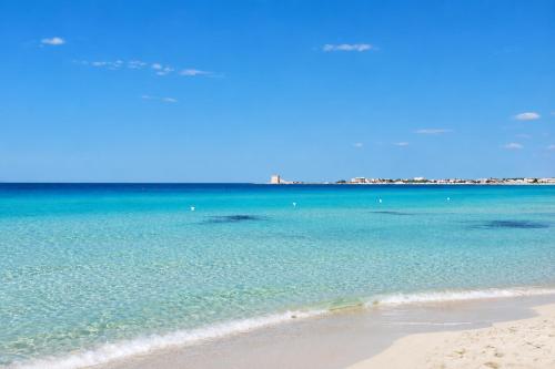 a view of a beach with the blue water at Hotiday Apartments Torre Lapillo in Porto Cesareo