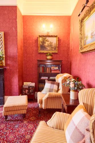 a living room with red walls with couches and a fireplace at Preston House in Abbeyleix