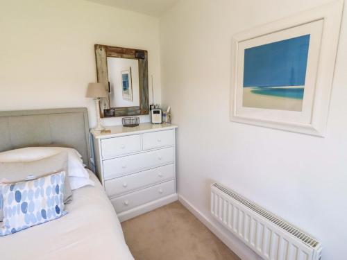 a bedroom with a bed and a dresser and a mirror at Dunford Cottage in Bamburgh