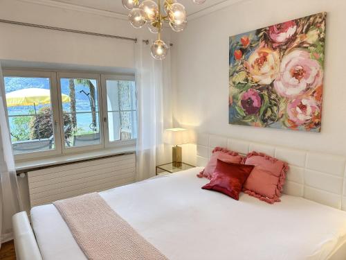 a bedroom with a white bed with red pillows at Villa Grande Dame by Fewotessin in Minusio
