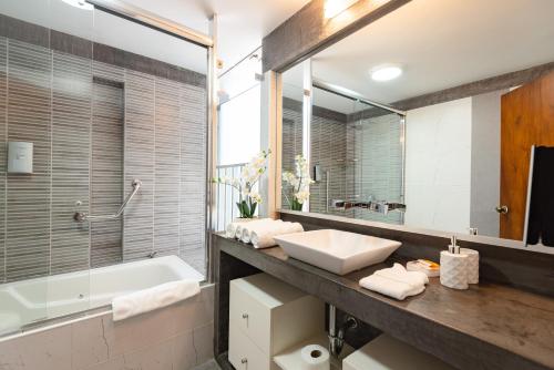 a bathroom with a sink and a tub and a mirror at OceanFront Larcomar Apartments in Lima
