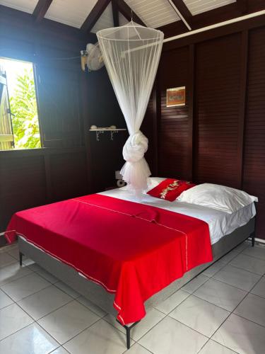 a bedroom with a bed with a red blanket at Cerise in Sainte-Anne