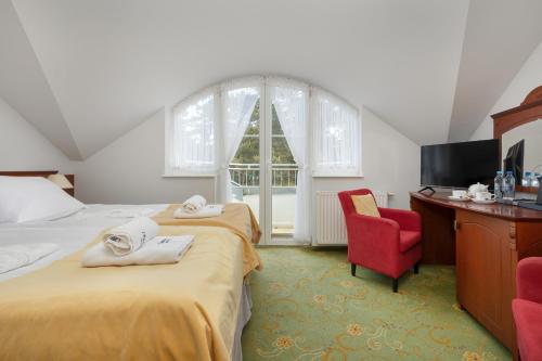 a bedroom with two beds and a tv and a chair at Chimera Spa Niechorze in Niechorze