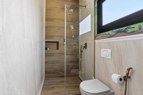 a bathroom with a toilet and a glass shower at Sunrise House - Swimming Pool in Berat