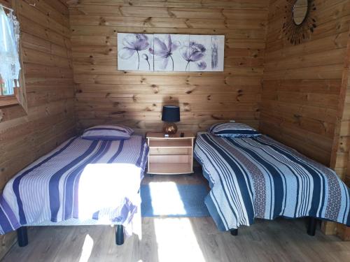 two beds in a room with wooden walls at chambres d'hotes et meublés les Hortensias in Lillers