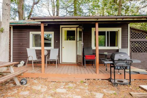 a cabin with a deck with chairs and a grill at Ambleside - 2-Bedroom Cottage #8 in Kawartha Lakes