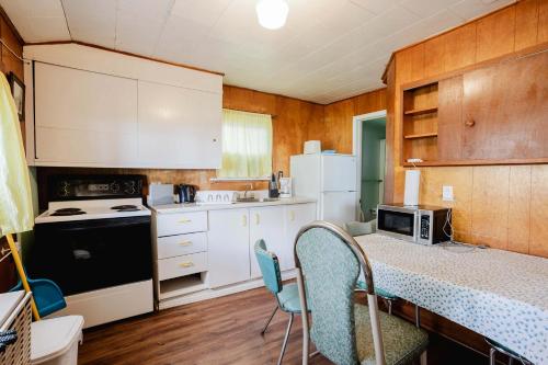 a kitchen with white cabinets and a table with chairs at Ambleside - 2-Bedroom Cottage #8 in Kawartha Lakes