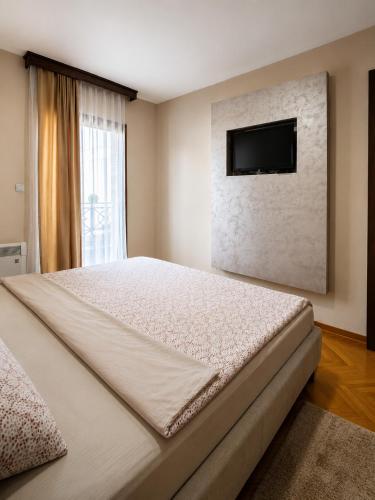a bedroom with a large bed and a flat screen tv at Duma Apartmani Vrnjačka Banja in Vrnjci