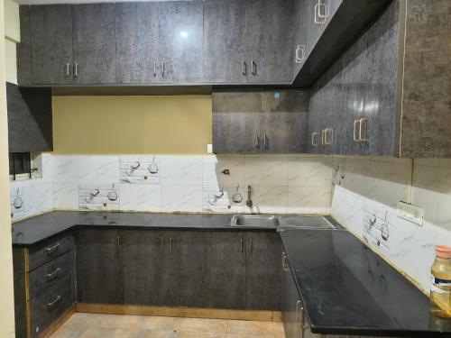a kitchen with gray cabinets and a black counter top at Stayvora Nest in Bangalore