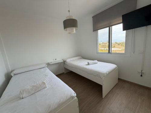 a white room with two beds and a window at Niza Beach Sunset Stay in Málaga
