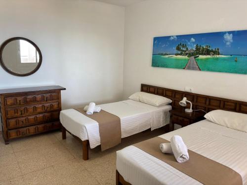 a hotel room with two beds and a mirror at Apartamentos Alba in San Antonio Bay