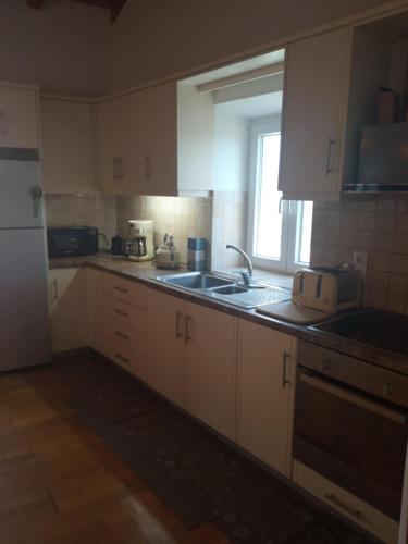 a kitchen with white cabinets and a sink and a window at The stone house in Doukádes