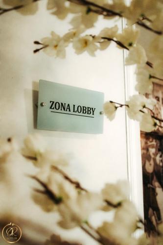 a sign for zona lobby on a wall with white flowers at OR HOTEL 94 in Barranquilla