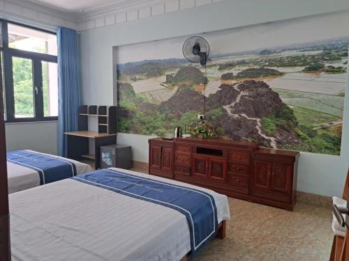 a bedroom with two beds and a painting on the wall at Tam Coc Guest House & Hostel in Ninh Binh