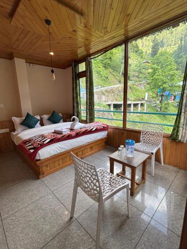 a bedroom with a bed and two chairs and a table at Venky's Shoja in Jibhi
