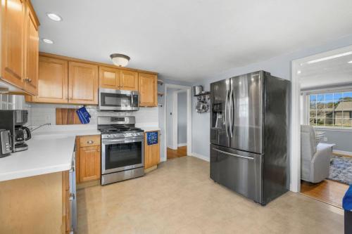 a kitchen with stainless steel appliances and wooden cabinets at Dog-Friendly Cape Cod Getaway with Fire Pit Yard in South Yarmouth