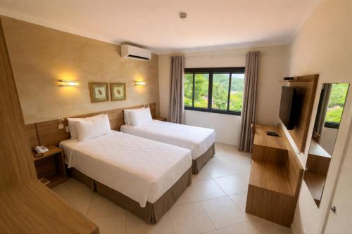a hotel room with two beds and a television at Guararema Parque Hotel in Guararema