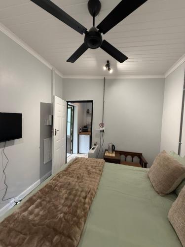 a bedroom with a large bed with a ceiling fan at Avo 1 on 27 Drew in Howick