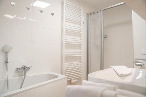 a white bathroom with a tub and a sink at Arber Lofts in Zwiesel in Zwiesel