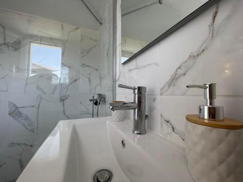 a white bathroom with a sink and a mirror at Alexandras Studio in Corfu