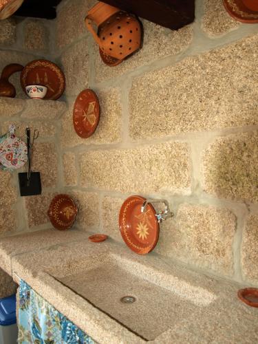 a kitchen counter with a sink and plates on the wall at Casa Das Videiras in Soajo