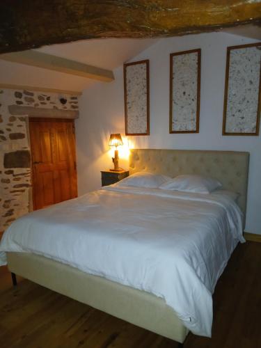 a bedroom with a white bed with a lamp on a table at Mas du pommier Gala in Gagnières