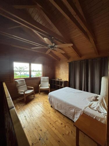 a bedroom with a bed and two chairs and a ceiling fan at Casa Franch in Deltebre