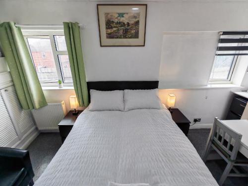 a bedroom with a white bed with two tables and two windows at Cherry Studio - Self Contained One-Bed Studio Flat in Oxford