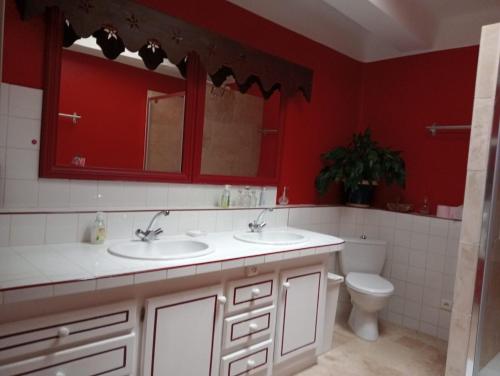 a red bathroom with two sinks and a toilet at Chambre d'hôtes in Puimoisson