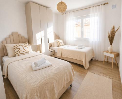 a white bedroom with two beds and a mirror at Villa Alera in Dobra Voda