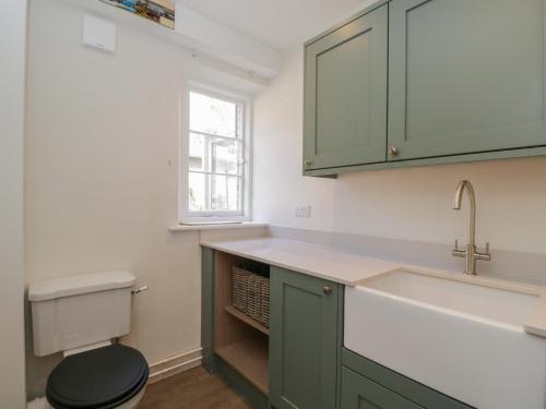 a bathroom with green cabinets and a toilet at Middle Cottage in Salisbury