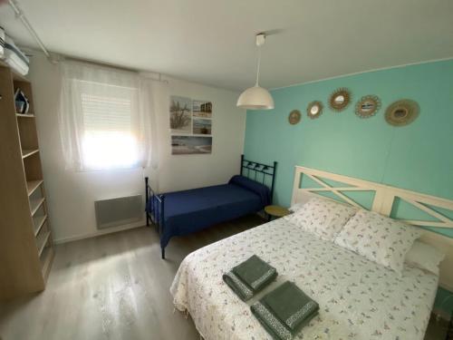 a bedroom with a bed and a blue chair at MAISON les ARCADES in Soustons