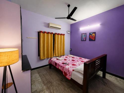 a bedroom with a bed and a purple wall at Royal Villa Pondy in Pondicherry